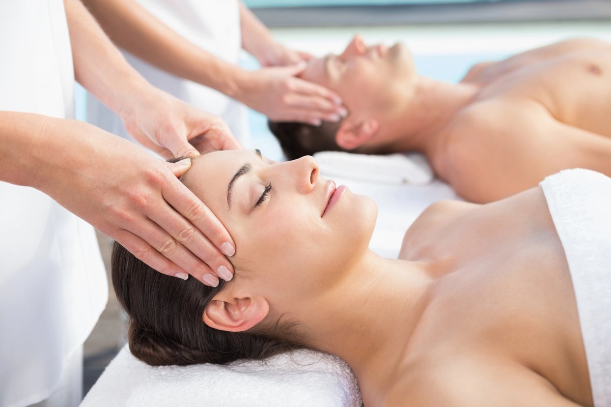 Couples receiving simultaneous head and shoulder massage treatment