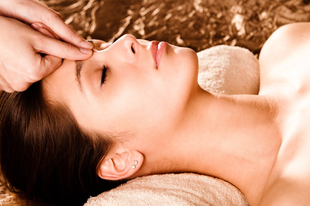 Woman receiving relaxing facial massage with natural oils